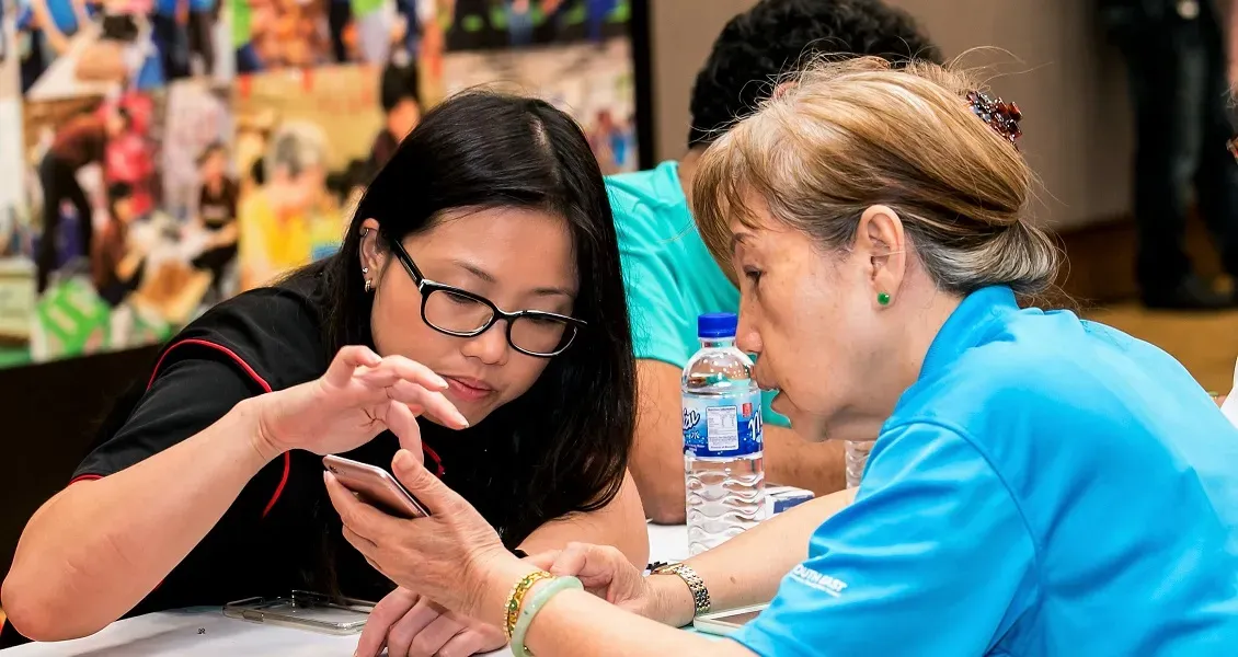Woman Guides Elderly Woman On Her Smartphone